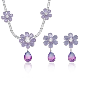 Elegantes Blumen-Schmuckset mit lila Kristallen und Tropfenanhängern auf weißem Grund