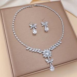 Detailed macro view of ziconia floral necklace and teardrop earrings set on a silk base