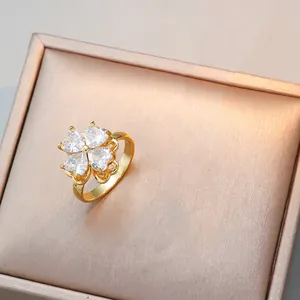 Détail d'une bague dorée ornée de zircons en forme de cœur avec un design de fleur de trèfle