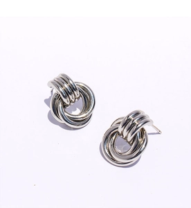 Détail de boucles d'oreilles nœuds à double anneau entrelacés en argent sur fond blanc