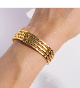 Detalle macro del brazalete ancho dorado de varias capas con texturas metálicas tejidas