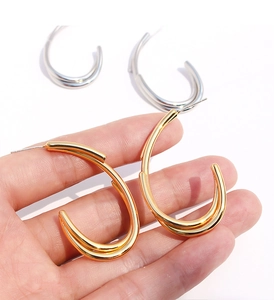 Détail de boucles d'oreilles créoles C en laiton doré et argenté au design géométrique poli