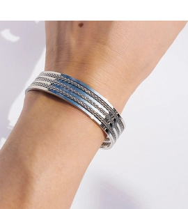 Primer plano de un brazalete ancho plateado con detalles de cadenas tejidas multicapa