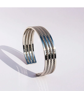 Primer plano de un brazalete multicapa plateado con textura de metal trenzado vintage