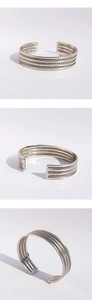 Detalle del brazalete de cadena plateada multicapa con textura tejida y diseño de banda abierta