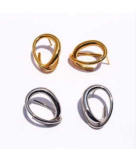 Close-up of geometric twisted line earrings in polished gold and silver metallic finishes