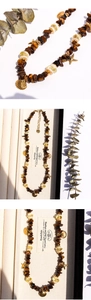 Détail du collier en œil de tigre avec breloques étoile de mer et coquillage dorés