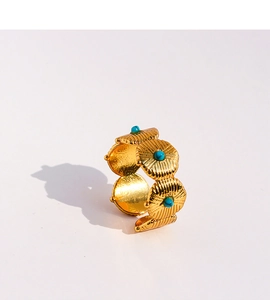 Détail d'une bague bohème dorée avec disques texturés et incrustations de turquoise