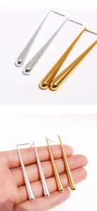 Détail de boucles d'oreilles pendantes en or et argent avec texture métallique et échelle