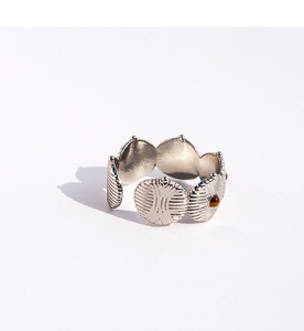 Détail d'un bracelet manchette en argent mat avec disques solaires et pierres œil de tigre