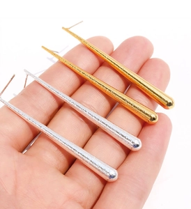 Détail de boucles d'oreilles pendantes avec texture métallique martelée en or et argent