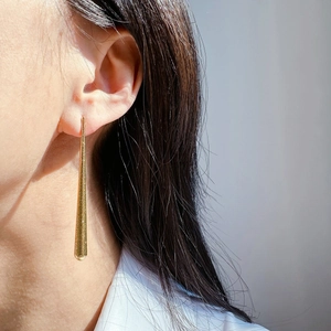 Détails de boucles d'oreilles pendantes dorées texturées portées pour affiner les traits du visage
