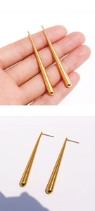 Détail macro de longues boucles d'oreilles dorées avec texture métallique et clous d'oreilles