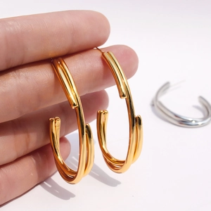 Boucles d'oreilles créoles croisées à trois couches en or et argent tenues à la main