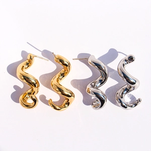 Détail de boucles d'oreilles spirales ondulées aux finitions or et argent polies