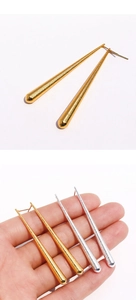 Détail macro de longues boucles d'oreilles coniques en métal texturé or et argent