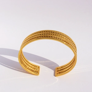Brazalete trenzado de tres capas en oro pulido con un estilo metálico minimalista