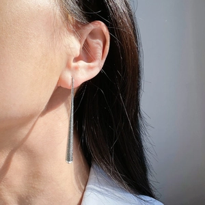 Boucles d'oreilles pendantes argentées avec texture métallique mate sur un mannequin