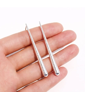 Gros plan de longues boucles d'oreilles argentées à texture martelée et design épuré