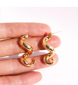 Gros plan sur des boucles d'oreilles spirales dorées au fini miroir et design courbé