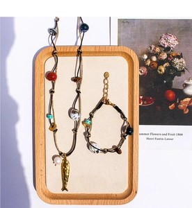 Dettaglio set collana e bracciale etnico con perle occhio di tigre e ciondolo a pesce