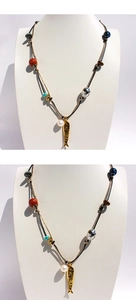 Dettaglio della collana artigianale con perline, ciondolo a pesce dorato e perle su busto