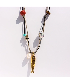 Dettaglio della collana artigianale con ciondolo a pesce d'oro, perle e pietre occhio di tigre
