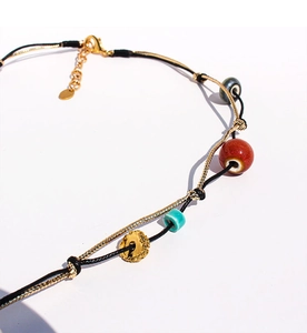 Dettaglio di collana fatta a mano con perle di ceramica colorate e catena d'oro