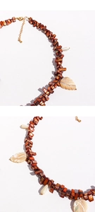 Macro shot of shell leaf pendants and beads on necklace with golden lobster clasp