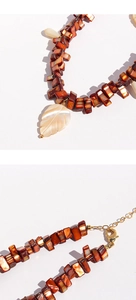 Detailed macro shot of natural shell leaf pendant and brown beaded necklace with gold clasp