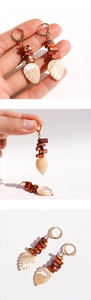Detail of beaded leaf earrings featuring natural mother-of-pearl and golden hoops