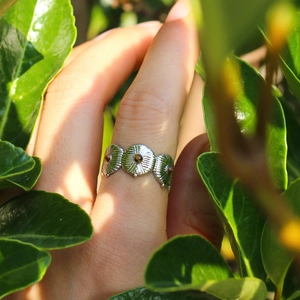 Bague rétro en argent avec trois pierres oeil de tigre sur fond de feuilles vertes