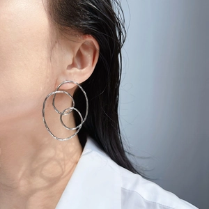 Gros plan de boucles d'oreilles créoles géométriques multicouches minimalistes