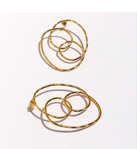 Détail de boucles d'oreilles dorées avec texture métallique martelée à la main