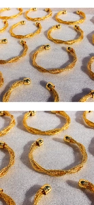 Dettaglio di bracciali a polsino intrecciati placcati oro con estremità sferiche lucide