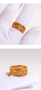 Détails d'une bague plaquée or avec motif évidé ondulé et zircons sur un gant de coton blanc