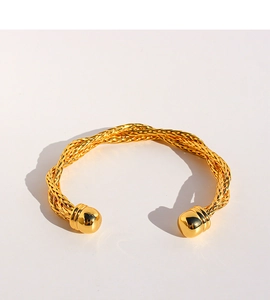 Dettaglio di un bracciale rigido a corda in ottone dorato con terminali a sfera