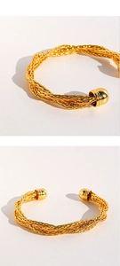 Vista macro del bracciale rigido in ottone placcato oro con trama a corda intrecciata