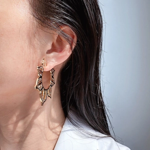 Nahaufnahme von goldenen Boho-Ohrringen mit radialem Sonnenmuster und floralen Schnitzereien
