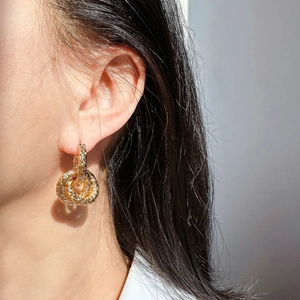 Vue rapprochée de boucles d'oreilles doubles anneaux dorés avec texture martelée