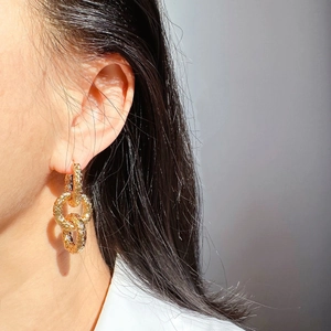 Gros plan de boucles d'oreilles dorées avec texture martelée sur un mannequin