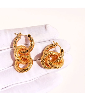 Détail macro de boucles d'oreilles dorées vintage avec texture martelée et anneaux liés