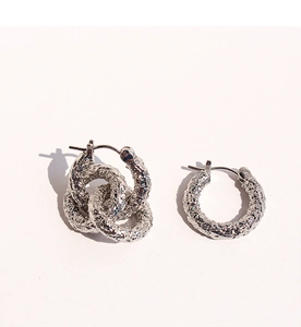 Détail de boucles d'oreilles argentées avec texture martelée et anneaux triples reliés
