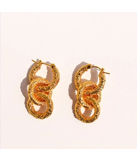 Détail de boucles d'oreilles dorées à texture martelée et design à trois cercles