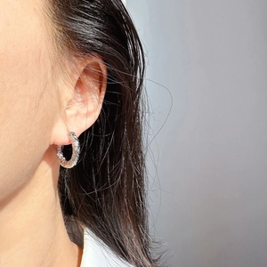 Gros plan d'une boucle d'oreille anneau martelée argentée texturée sur un mannequin
