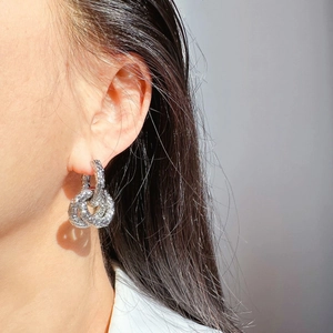 Gros plan de boucles d'oreilles créoles torsadées argentées ornées de pavé de zirconiums