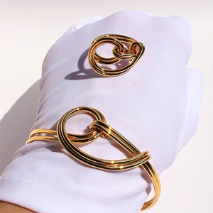 Detailed view of gold knot bangle and ring set worn on model with elegant metal weaving