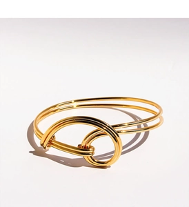 Detailed view of polished gold double-layered wire knot bracelet with interlocking design