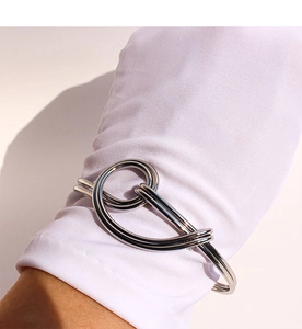 Close-up of a silver-finish metal knot bangle with polished double-layered hollow design