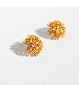 Close-up of vintage firework pearl stud earrings with gold plating and radial cluster design